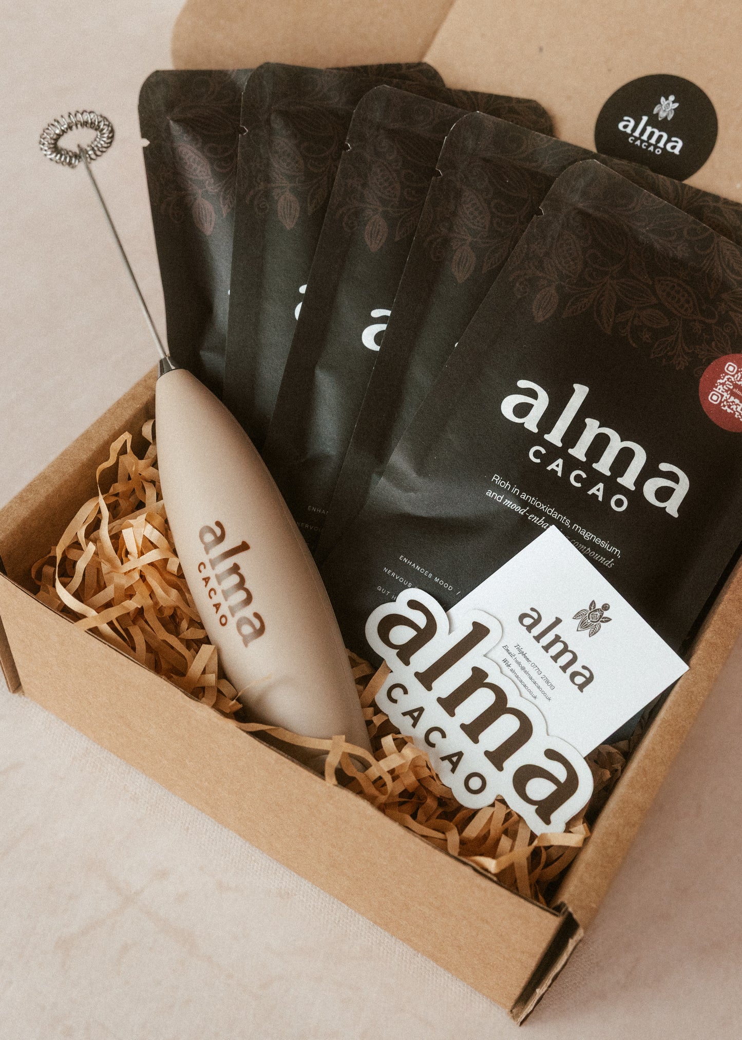 Box of Alma Cacao products including sachets and a milk frother.