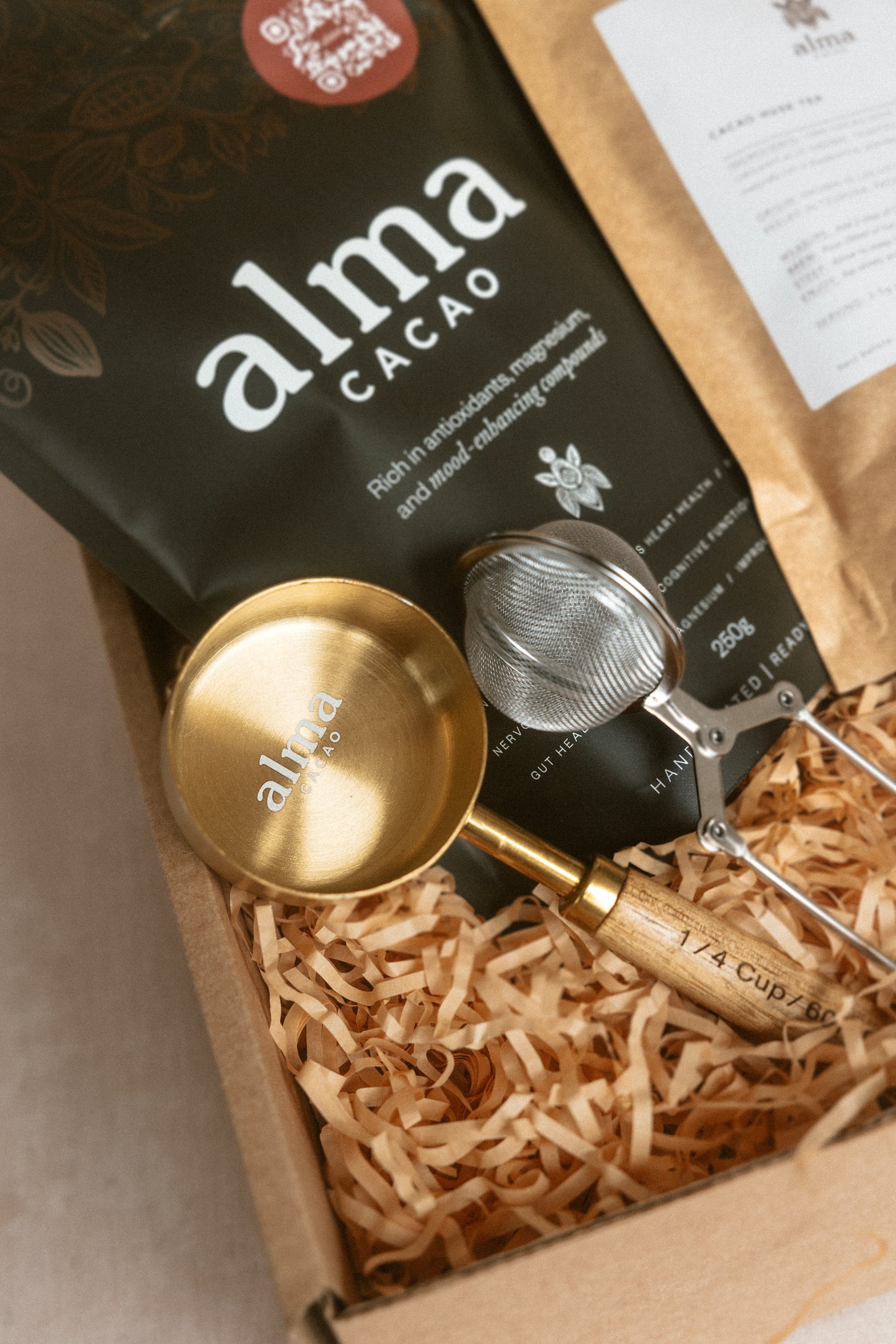 Cacao packaging with a gold scoop and strainer on a beige background